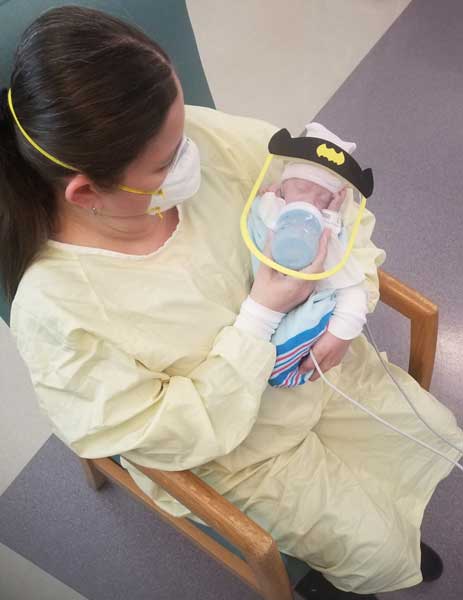 Staff member feeding baby with face shield