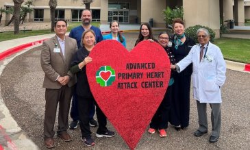 Employees of DHL standing with a heart-shaped sign that reads 'Advanced Primary Heart Atttack Center'