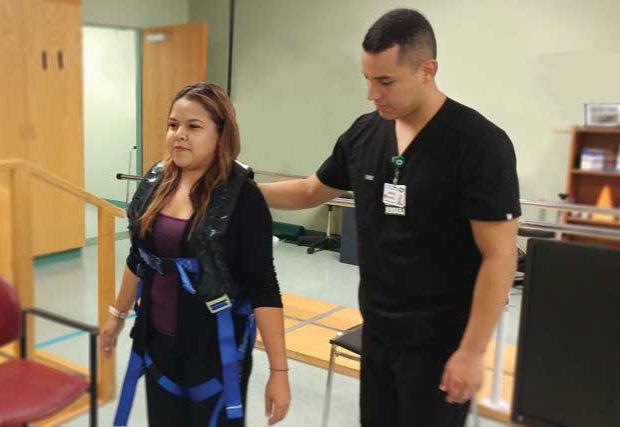 Patient using unique harness system with healthcare provider standing nearby