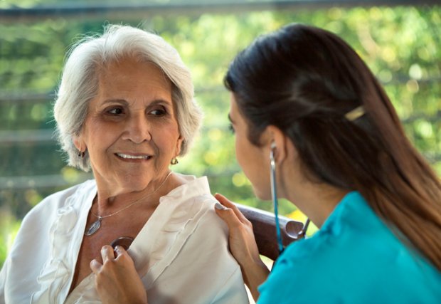 Female physician listens to senior patient's heart